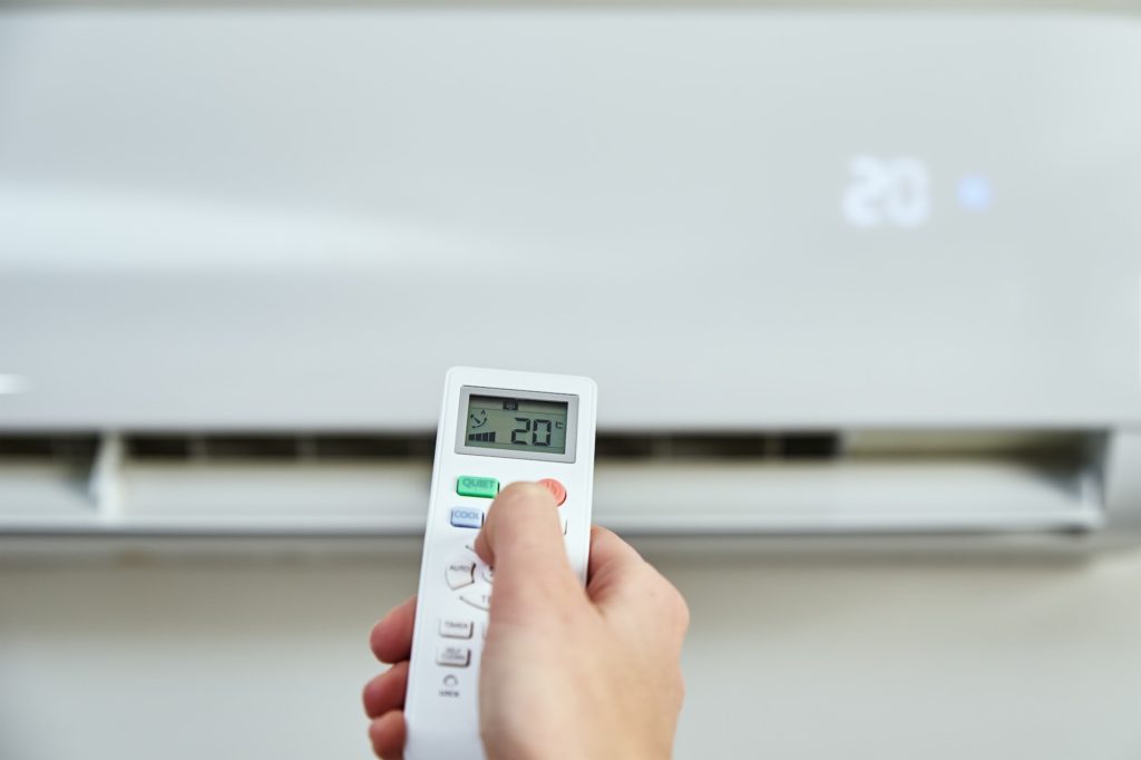 Hand adjusting temperature on air conditioner