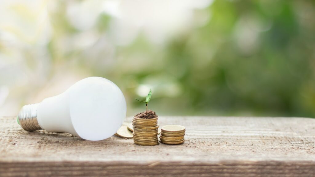 LED bulb on coin stacks with growing plant - Concept of saving energy, electric and eco business
